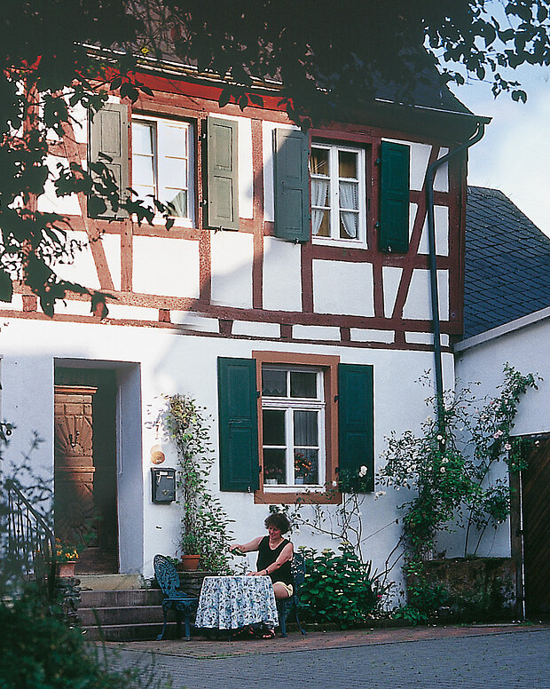 Frau Wagner sitzt vor dem Ferienhaus und gießt ein Glas Wein ein